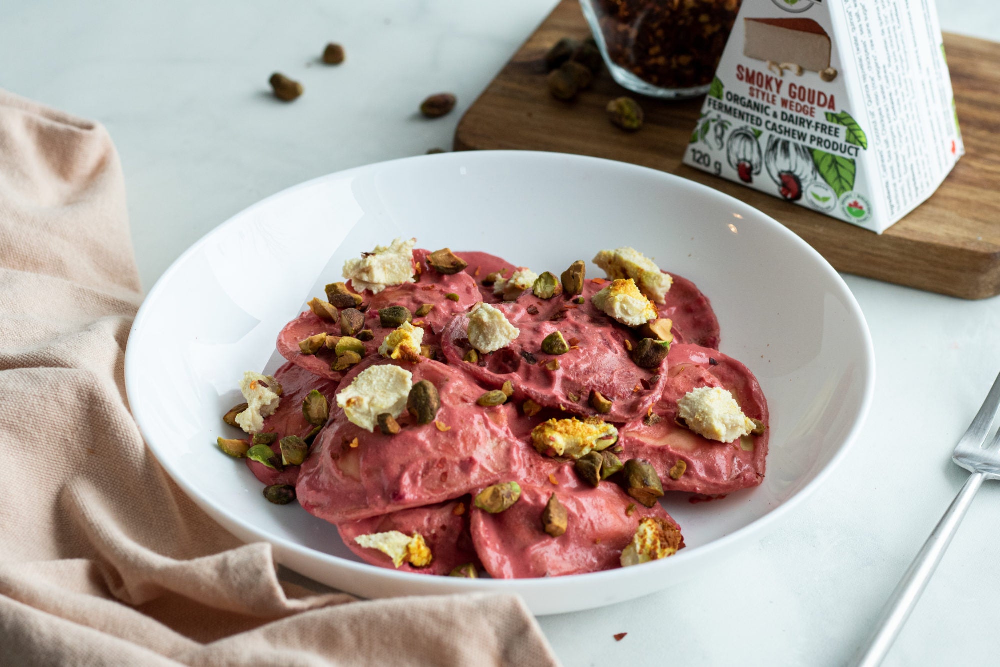 Bol de raviolis de betteraves roses, sans produits laitiers, garnis de noix et de gouda fumé sans produits laitiers.