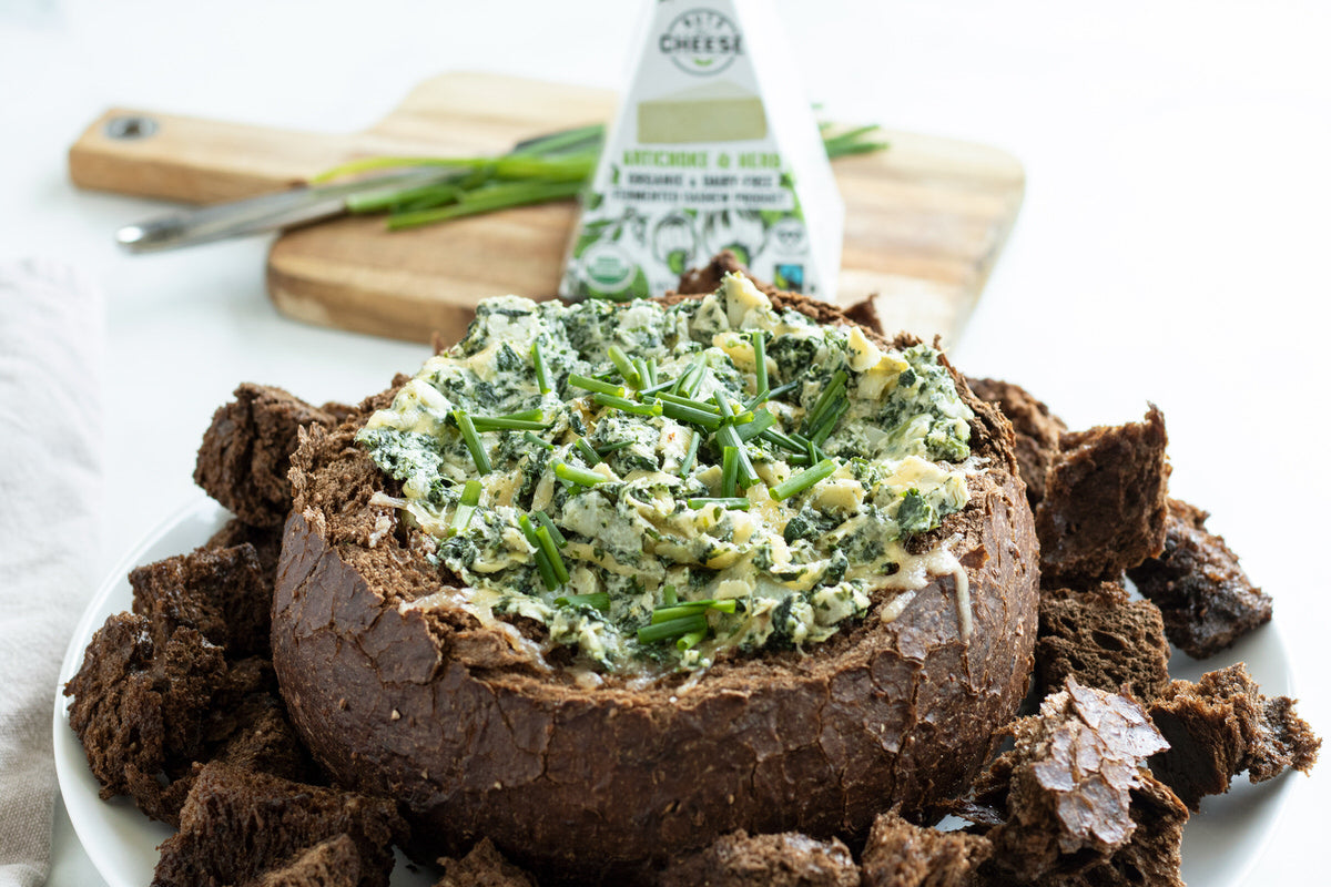 Bol de pain farci d'une trempette végétalienne aux épinards faite d'artichauts et de fromage aux herbes sans produits laitiers.