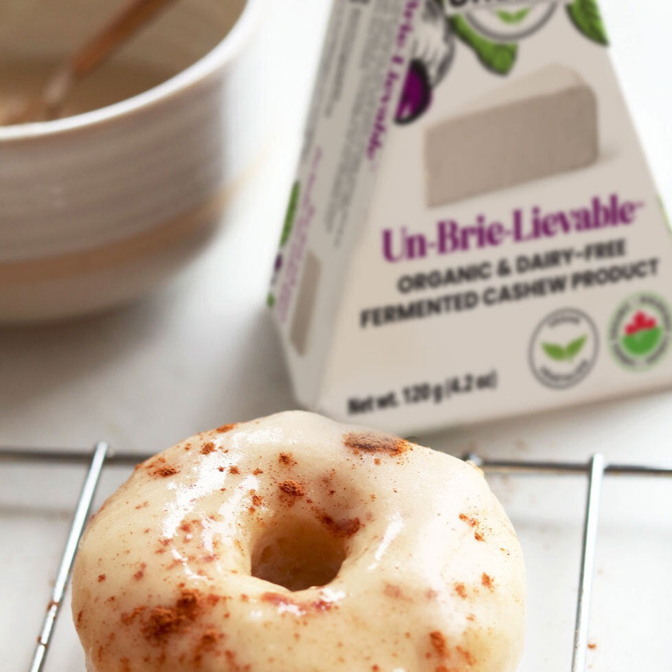 beignets végétaliens glacés au fromage brie et à la cannelle avec un paquet de cales de fromage brie Un-Brie-Lievable™ fermenté biologique et sans produits laitiers Nuts For Cheese™ .